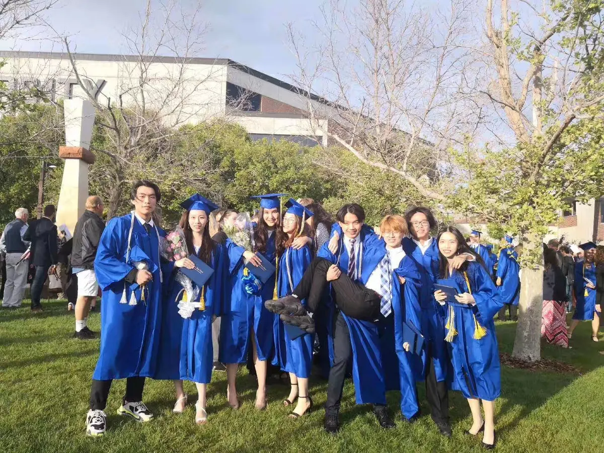 中国学生穿毕业服在美国学校毕业典礼现场集体合影